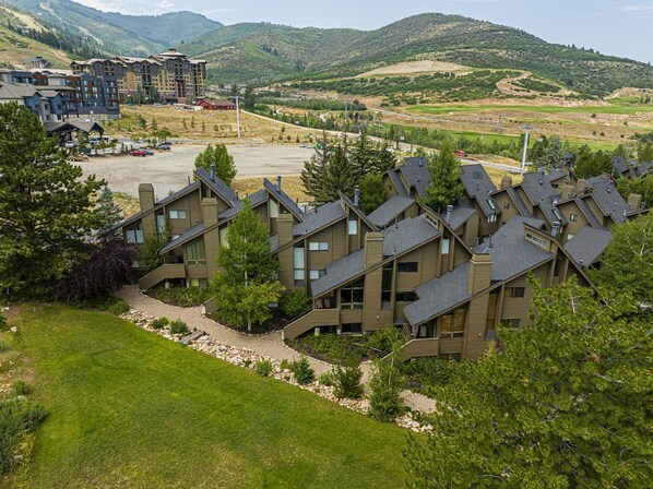A residential area with modern houses, a parking lot, and a mountainous backdrop.