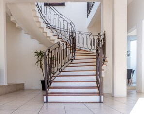 A modern staircase with a metal railing, white walls, and a tiled floor. - Villa Catalina (Oaxaca)