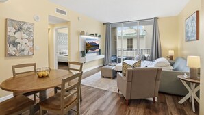 Ein Hotelzimmer mit Essbereich, einer Couch, einem Fernseher und einem Balkon mit Blick.