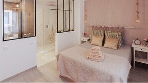 Een moderne slaapkamer met een groot bed, een inloopdouche en nachtkastjes met lampen.
