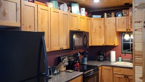 A kitchen with wooden cabinets, a refrigerator, a microwave, and a stove. - River Ridge Cottage (Spooner)