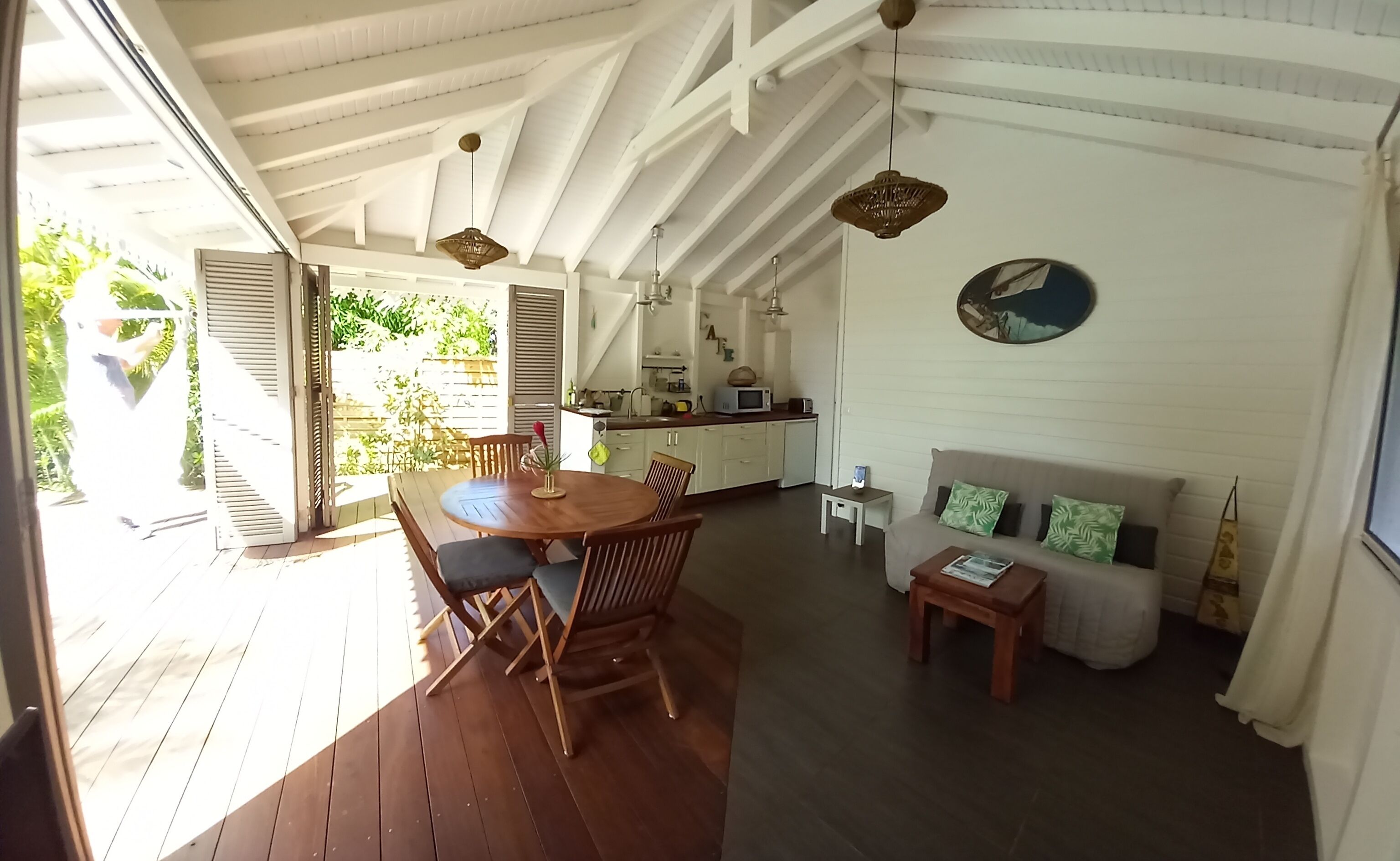 A spacious living area with a wooden dining table, a sofa, and a kitchen area with a microwave.