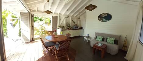 A spacious living area with a wooden dining table, a sofa, and a kitchen area with a microwave.