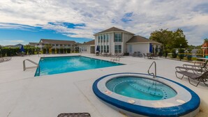 A swimming pool with a hot tub, lounge chairs, and a building with large windows. - LOCATION**LOCATION**LOCATION (Gulf Shores)