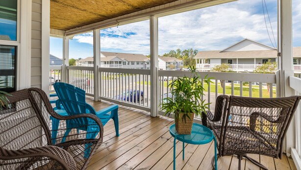 A covered porch with wicker chairs, a small table, and a potted plant. - LOCATION**LOCATION**LOCATION (Gulf Shores)