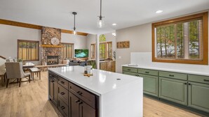 Una cocina moderna con una isla grande, armarios de madera y una chimenea de piedra.