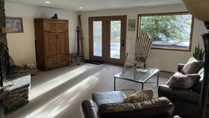 A living room with a leather sofa, a glass coffee table, a wooden cabinet, and a ski rack.