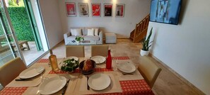 Uma área de refeições com mesa posta para quatro pessoas, um sofá e uma escada.
