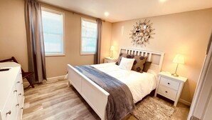 A bedroom with a bed, nightstands, a dresser, and a decorative wall piece. - Westside ^Cottage^ (Redding)