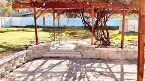 A covered patio area with a brick floor and wooden pergola. - Westside ^Cottage^ (Redding)