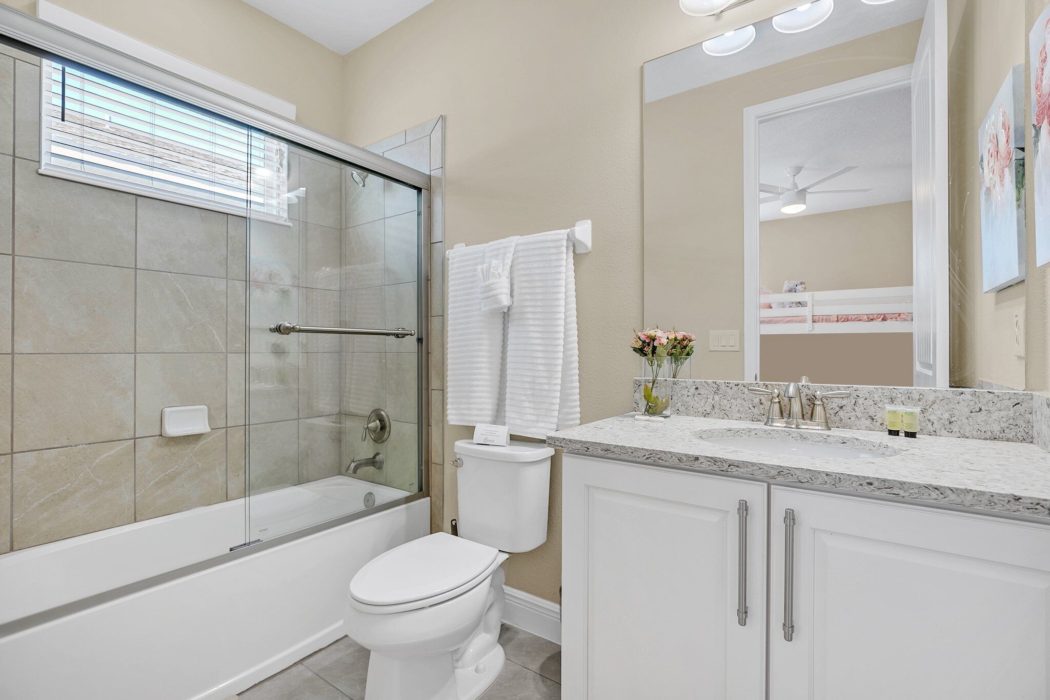 A modern bathroom with a glass-enclosed shower, a white toilet, and a vanity with a marble countertop.