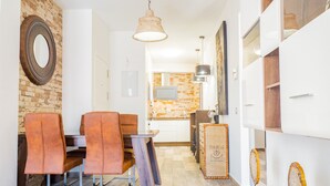 A modern kitchen with a brick backsplash, a dining area with leather chairs, and a wooden cabinet with a 'PARIS' label.