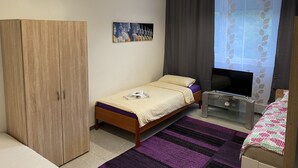 Un dormitorio con cama, televisor, armario y un cuadro en la pared.