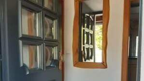 A room with a dark wooden door, a small window with a wooden frame, and a tiled floor. - Vacation home Zum Unneschmitz, near the Rhine/Moselle, (Udenhausen)