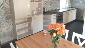 A kitchen with a wooden table, a vase of flowers, and a coffee cup. - Vacation home Zum Unneschmitz, near the Rhine/Moselle, (Udenhausen)
