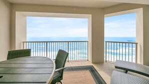 Un balcon avec une table et des chaises, donnant sur une plage et l’océan.