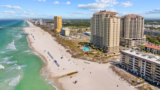 Un paysage urbain côtier avec une plage, des immeubles de grande hauteur et un ciel dégagé.