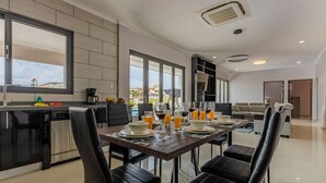 A modern kitchen with a dining area, featuring a large window, a built-in oven, and a dining table set for four. - NEW 6BR Villa w/ Pool across street @ PalmBeach (Noord)