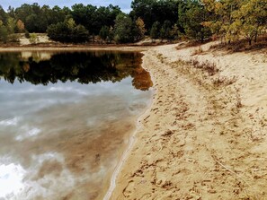 A sandy beach with a calm lake, surrounded by trees. - Summer Fun in Necedah WI at Lazy Moose Lodge! (Necedah)