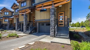 A modern multi-story residential building with a stone facade, multiple garage doors, and a welcoming entrance.