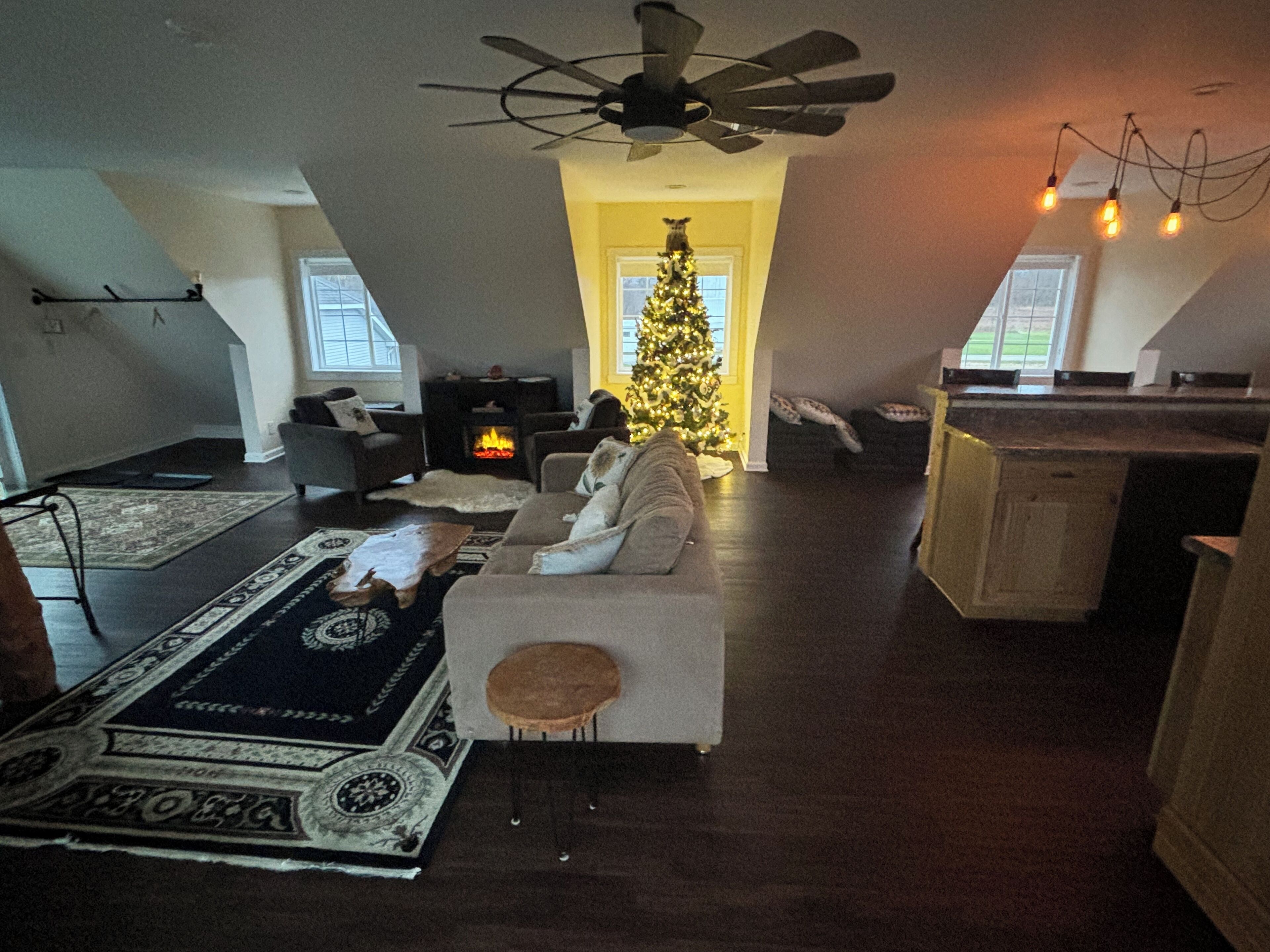Ein gemütliches Wohnzimmer mit Kamin, Weihnachtsbaum und Deckenventilator.