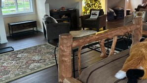 Uma sala de estar acolhedora com um banco de madeira, um sofá e um pinheiro de Natal.