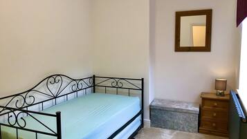 A single bed with a metal frame and a light blue mattress in a room with white walls.