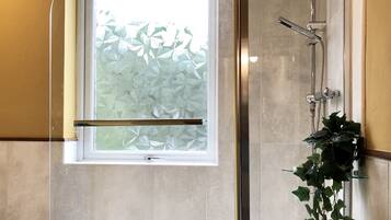 Un bagno moderno con doccia vetrata, una vasca e una finestra vista vegetazione.