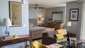A hotel room with a bed, a desk, a chair, a dining table, and a mirror. - One Bedroom Direct Gulf Front View (FORT MYERS)