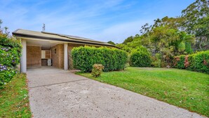 A residential property with a covered driveway, brick exterior, and a well-maintained garden.