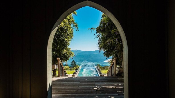 An arched doorway leading to a pool with a mountain view.