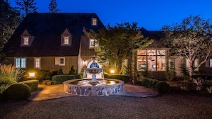 A house with a fountain in the center, surrounded by a well-maintained garden.