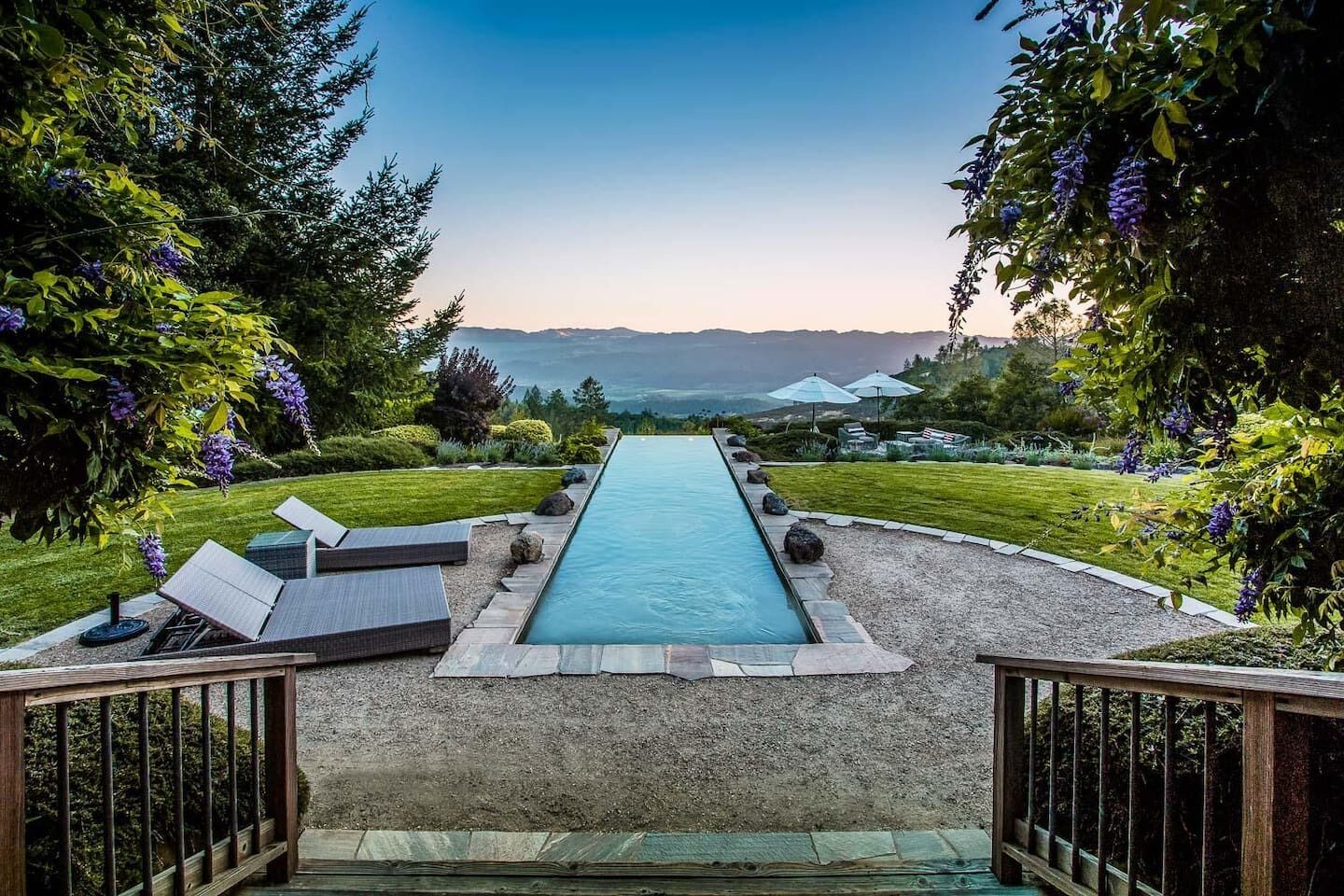 Una piscina con vistas a montañas, rodeada de vegetación y tumbonas.