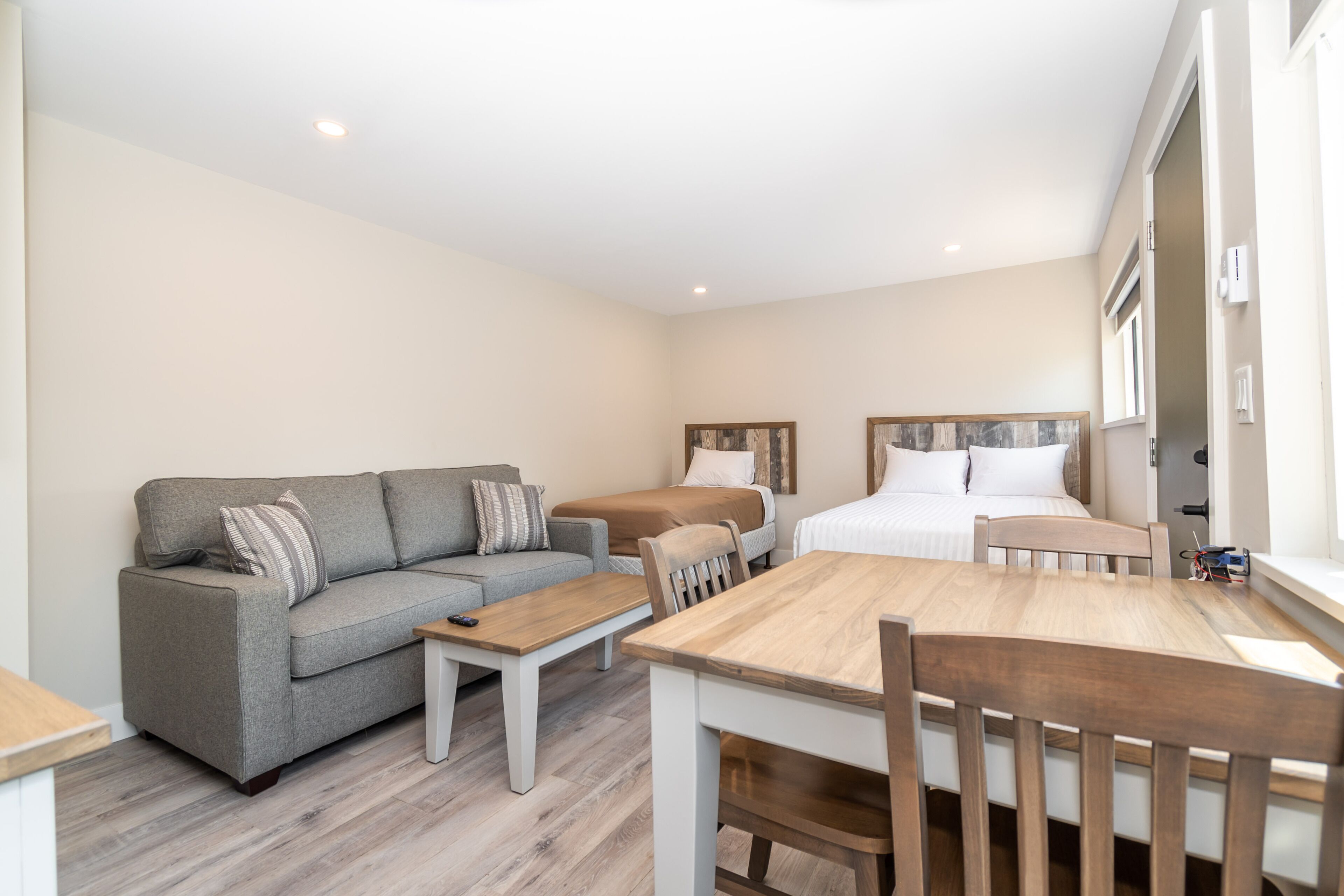 A compact living space with a sofa, a bed, a dining table, and a small kitchen area.