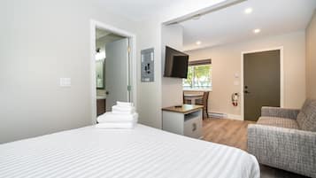 A hotel room with a bed, a desk, a chair, and a television.