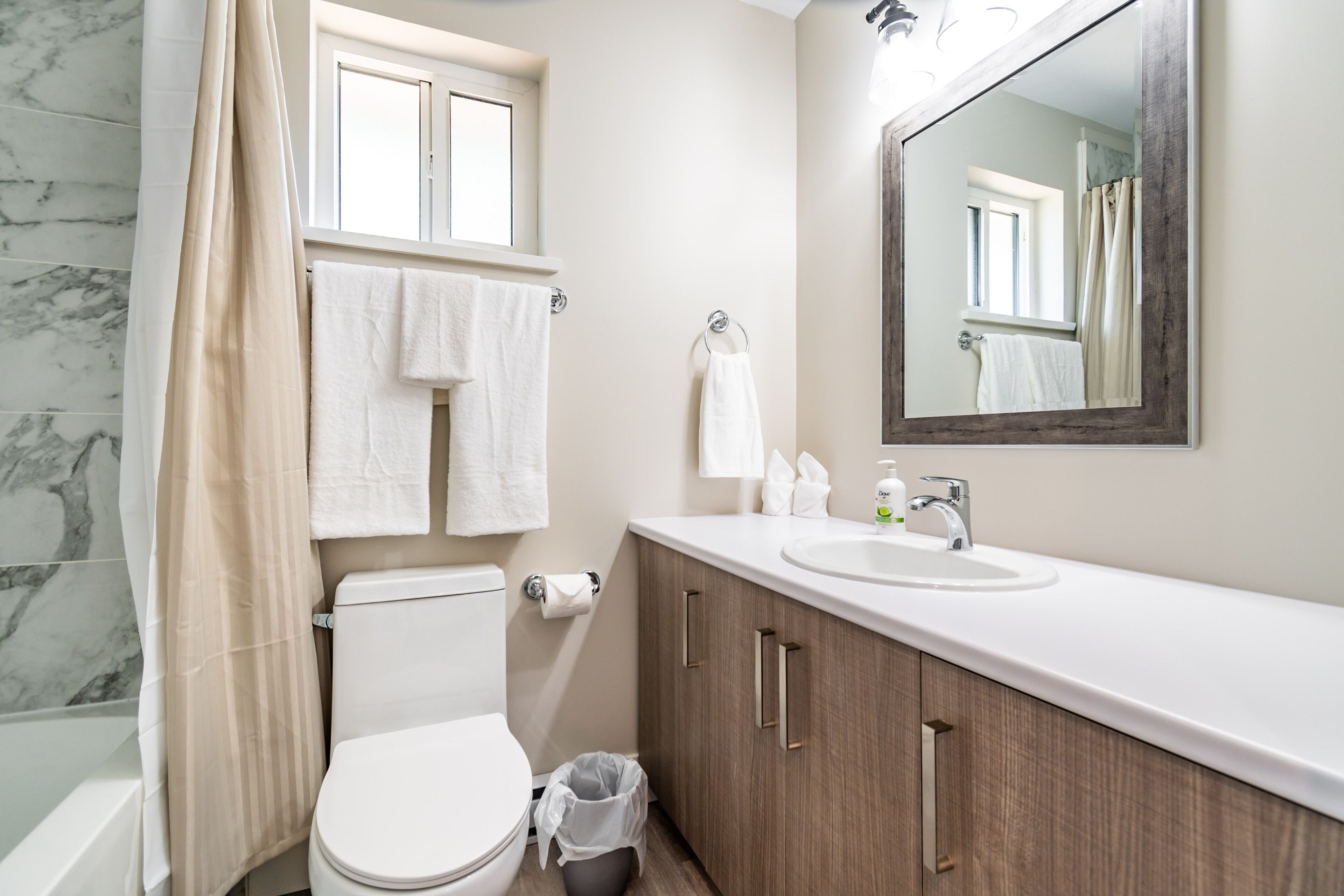 Un baño con inodoro, lavabo, espejo y cortina de ducha.