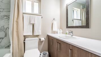 Un baño con inodoro, lavabo, espejo y cortina de ducha.