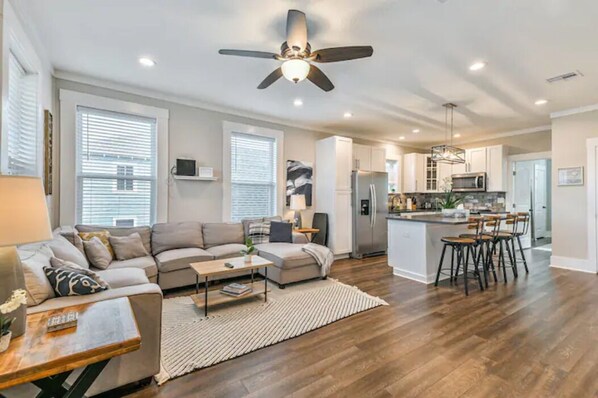 A modern living room with a sofa, coffee table, and a dining area with chairs.