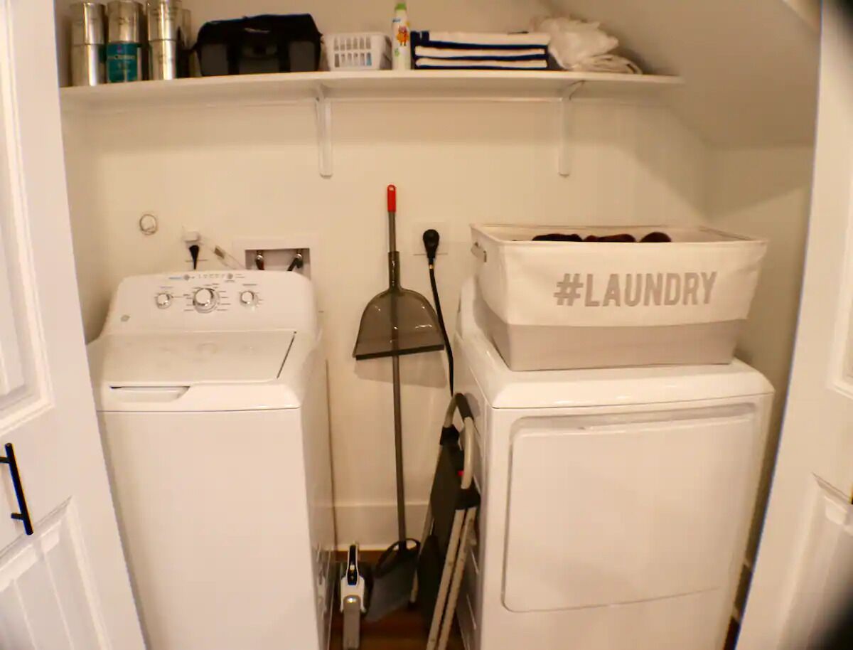 Et vaskerum med vaskemaskine, tørretumbler og en #laundry kurv ovenpå tørretumbleren.