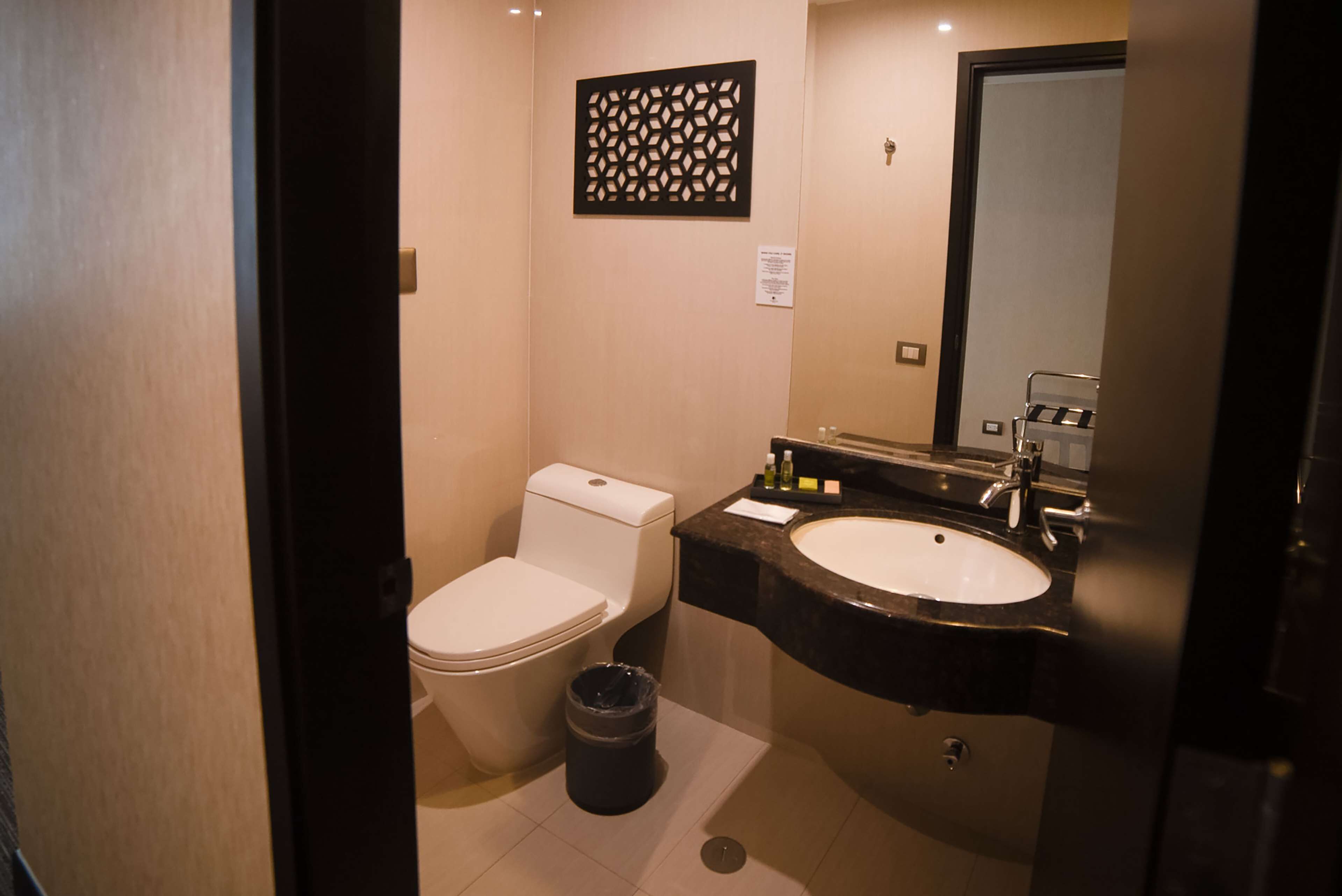 A compact bathroom with a toilet, sink, and mirror.