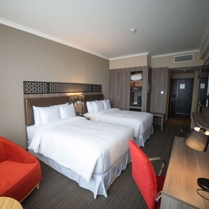A hotel room with two beds, a desk, a chair, and a small table. - DoubleTree by Hilton Trujillo (Víctor Larco Herrera)