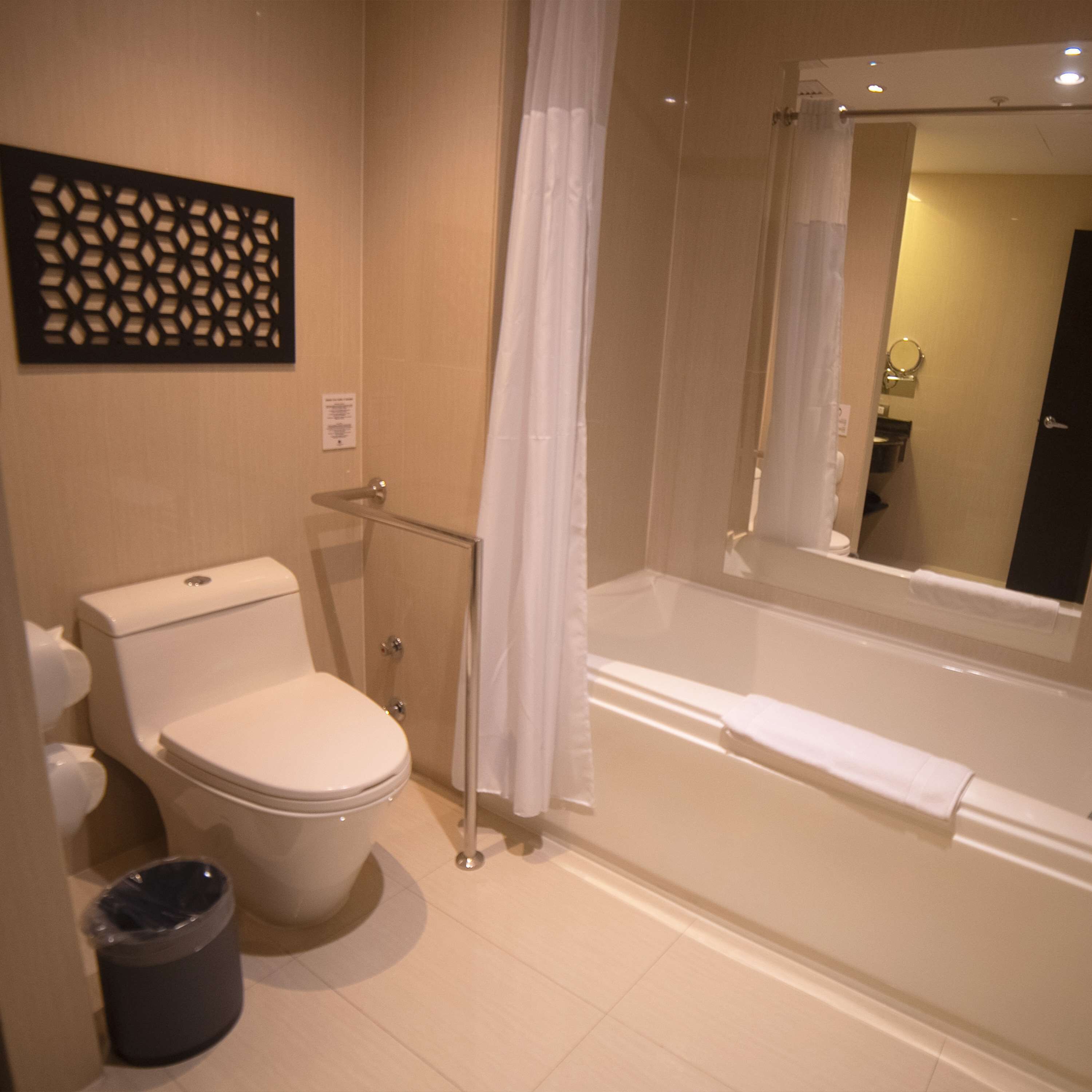 Ein Badezimmer mit Toilette, Mülleimer, Dusche mit Glastür und Badewanne.