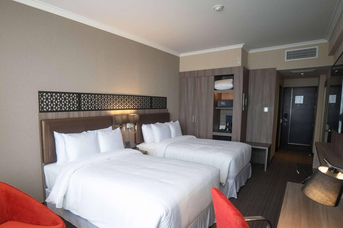 Una habitación de hotel con dos camas, un escritorio, una silla y una mesita.