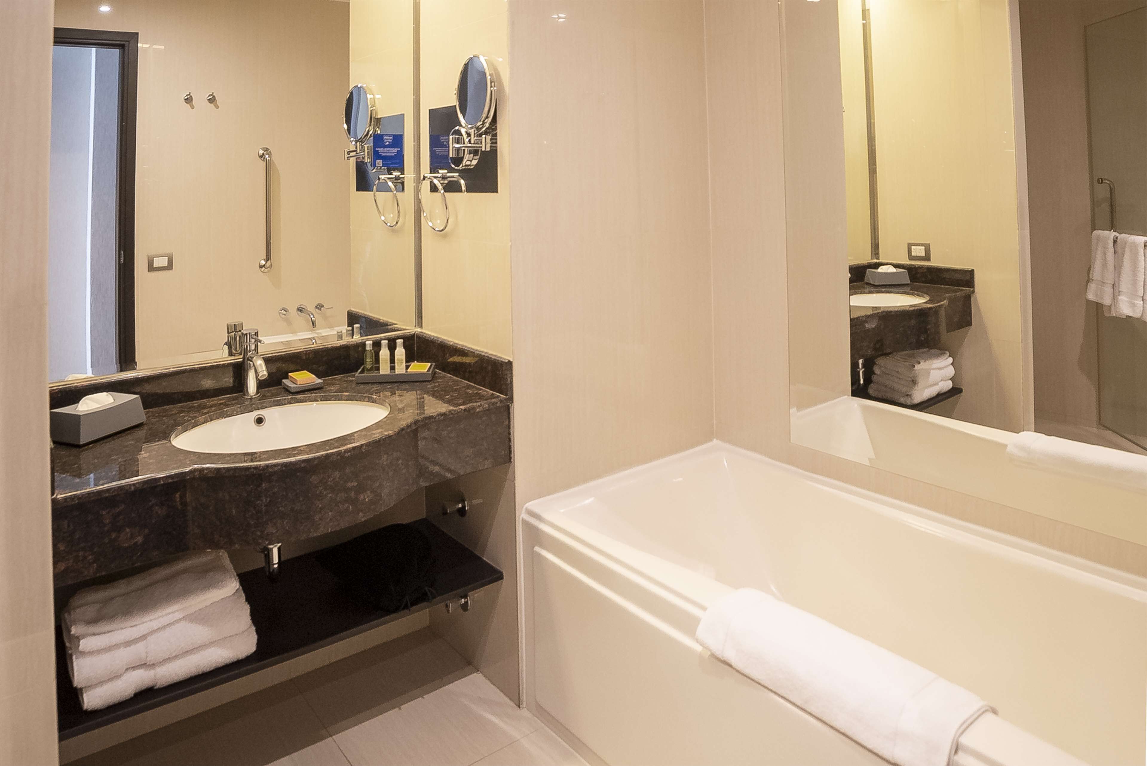 Un baño moderno con bañera, dos lavamanos, tocador y un espejo grande.