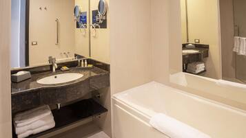 Un baño moderno con bañera, dos lavamanos, tocador y un espejo grande.