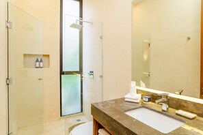 A modern bathroom with a glass shower enclosure, a marble sink, and a large mirror.