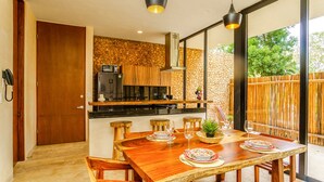 Una cocina moderna con salpicadero de piedra, armarios de madera y una zona de comedor con mesa y sillas de madera.