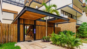 Un edificio moderno con fachada de madera, un acceso cubierto y un muro de piedra.