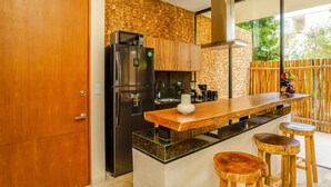 Una cocina moderna con refrigerador empotrado, armarios de madera, encimera de granito y una barra con taburetes.