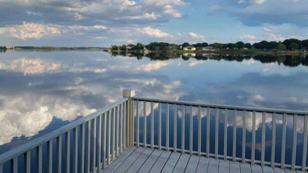 Ein ruhiger See mit einem hölzernen Deck und einem Geländer im Vordergrund.